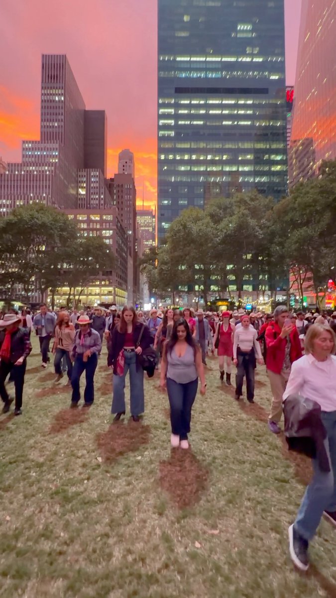 Dozens of people line dancing under a movie-like sunset in Midtown Manhattan